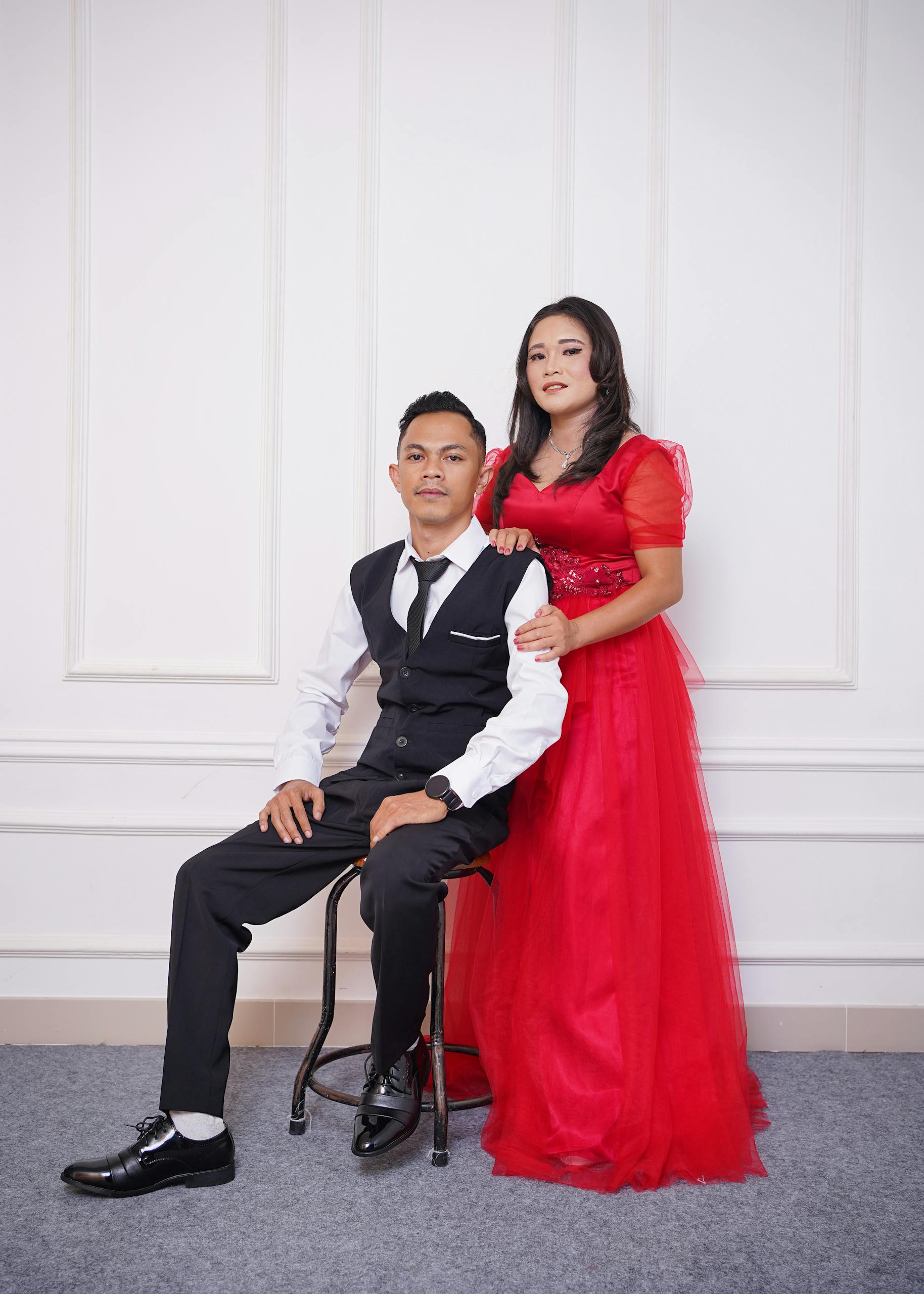 Stylish couple in elegant formal wear posing indoors, exuding sophistication and grace.