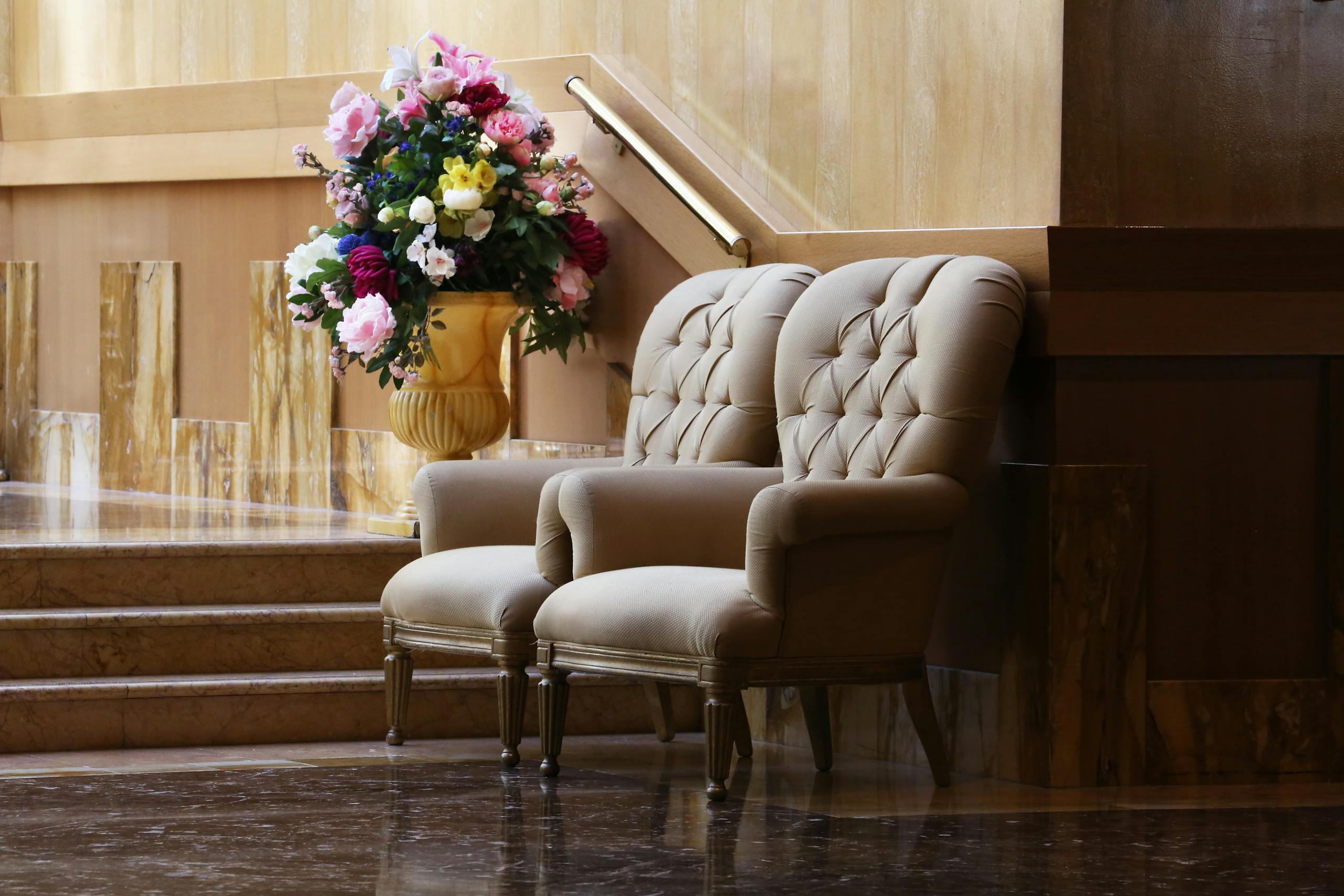 Two elegant tufted chairs and a floral arrangement in a luxurious interior.